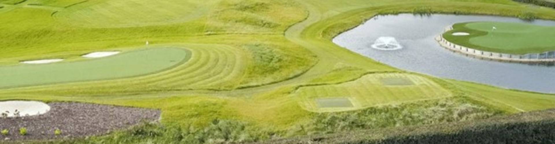 Golf course landscape with artificial turf putting greens near a water feature, designed for durable and low-maintenance play.